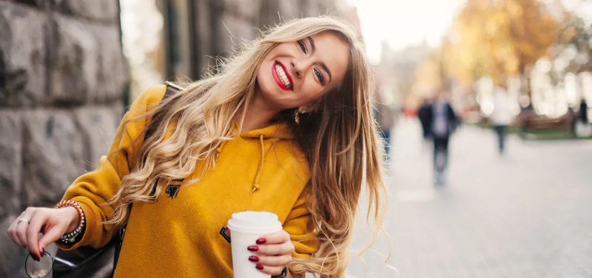 young woman in a yellow sweater smiling, showing off her cosmetic dental work in Charlotte