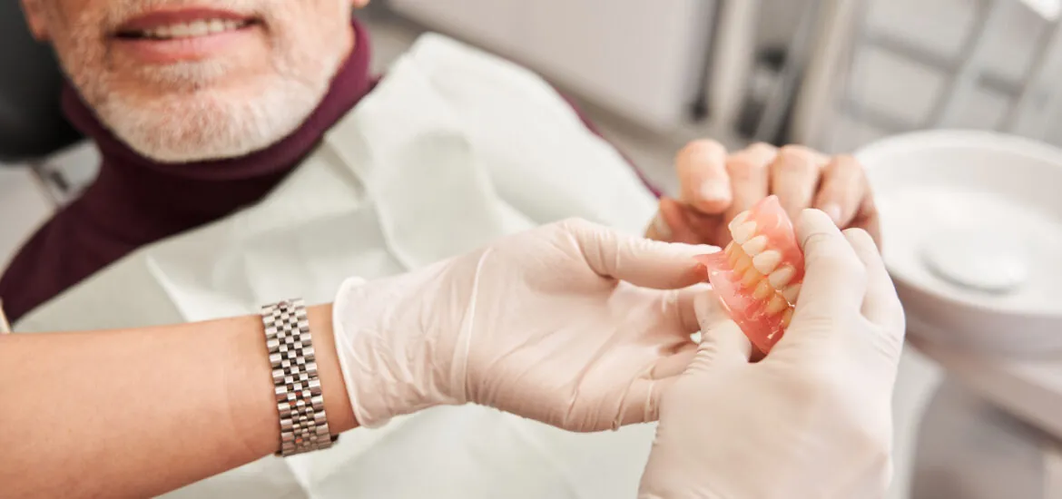doctor showing a pair of dentures to a patient in Charlotte