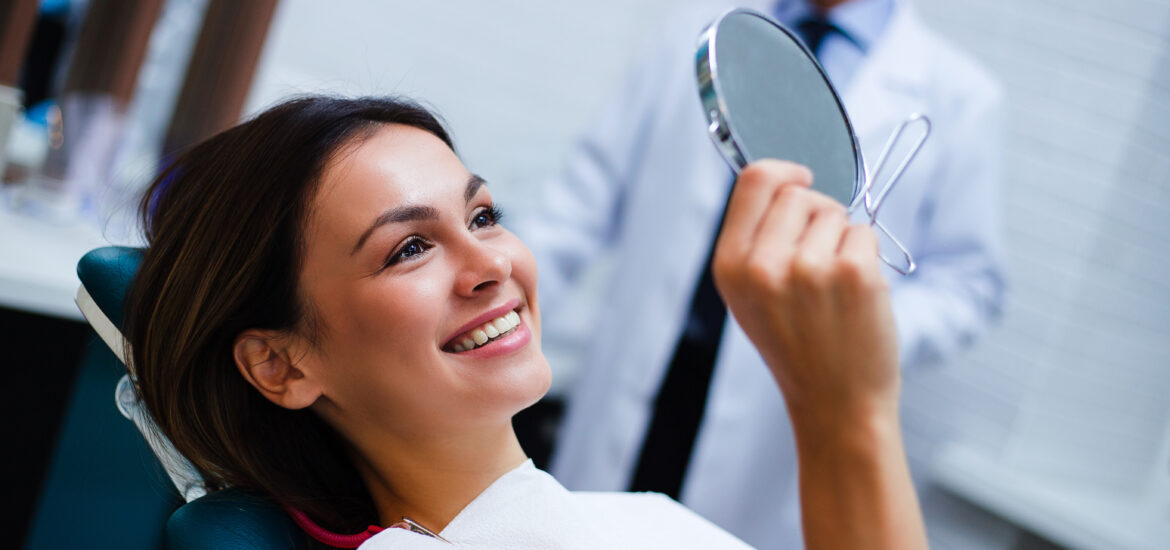 young woman in a dental chair smiling, happy new dental implants