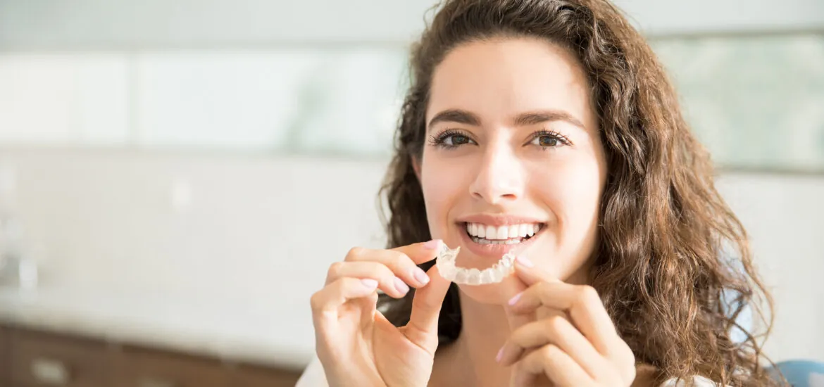 smiling woman putting in her new clear aligners