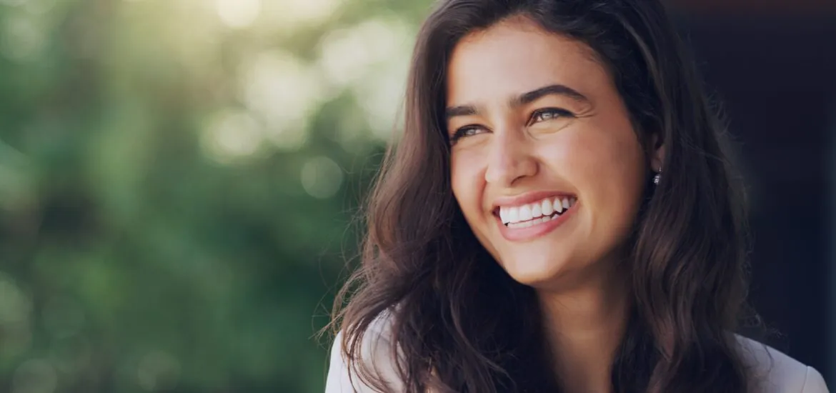 young woman outdoors smiling, perfect white teeth