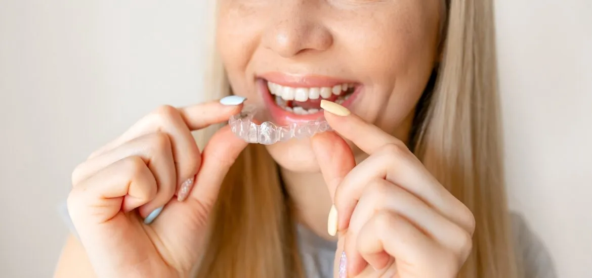 young woman holding up clear aligners